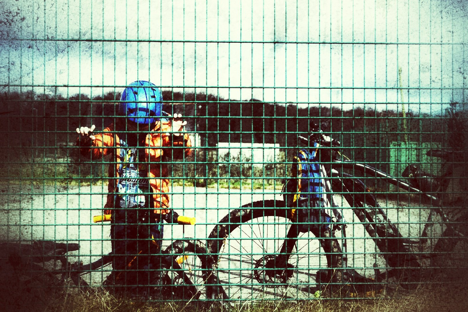 Mountain bikes and riders seen through a wire fence