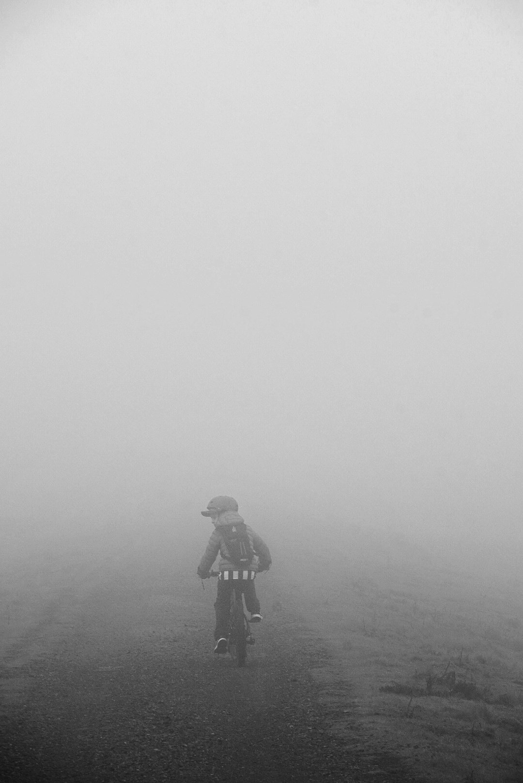 Lone cyclist riding into moorland fog