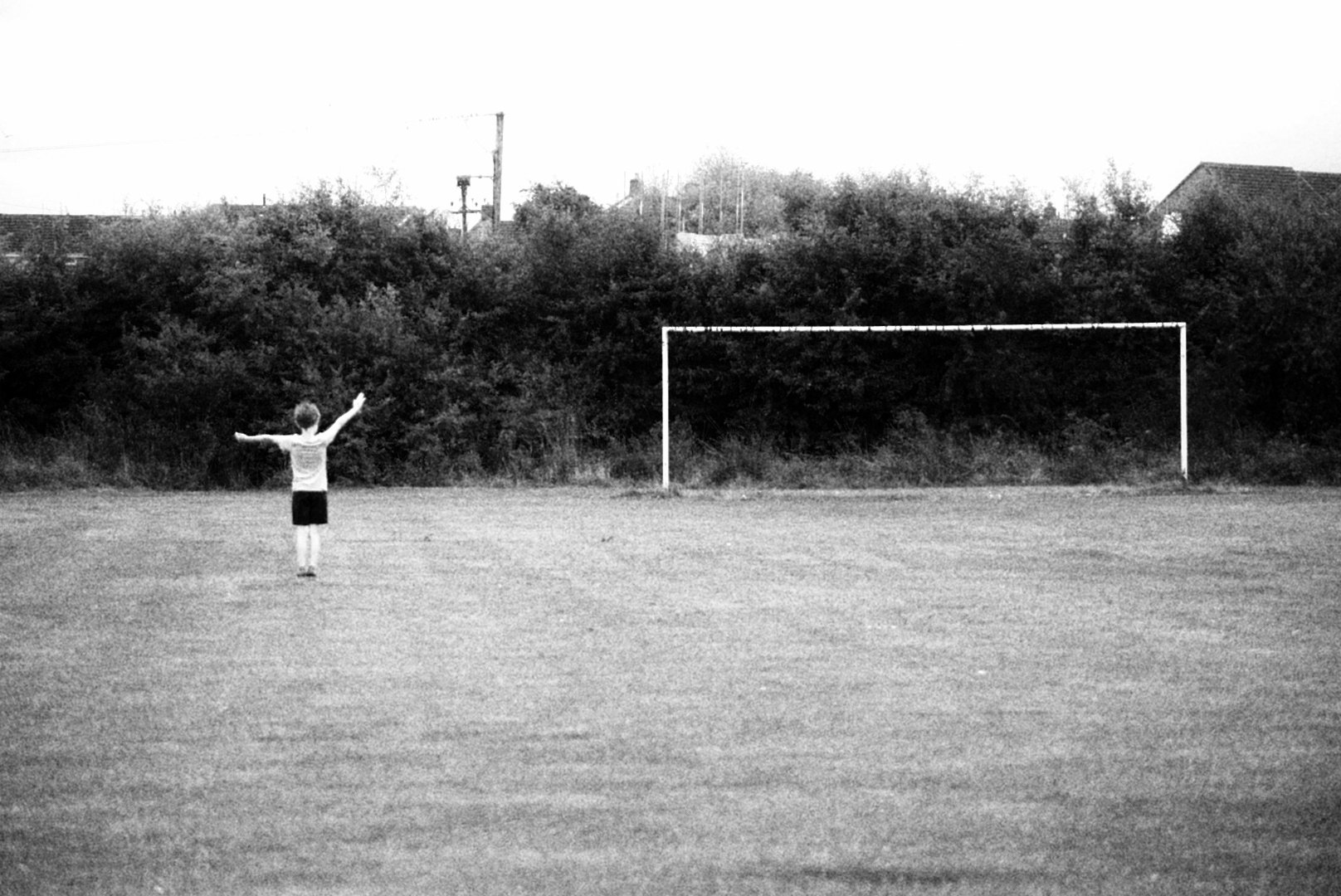 Child with arms spread wide in front of a football goal